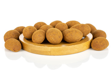 Lot of whole sweet brown chocolate cinnamon almond on round bamboo coaster isolated on white background
