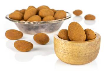 Lot of whole sweet brown chocolate cinnamon almond in tiny wooden bowl in metal bowl isolated on white background
