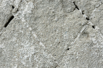 Concrete wall with fine marble chips. Deep cracks are filled with light crystals.