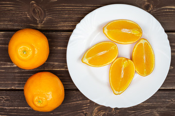 Group of two whole four quarters of fresh orange tangelo minneola on white ceramic plate flatlay on...