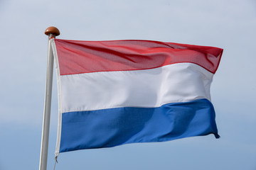 Dutch flag waving against blue sky