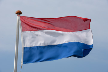Obraz na płótnie Canvas Dutch flag waving against blue sky