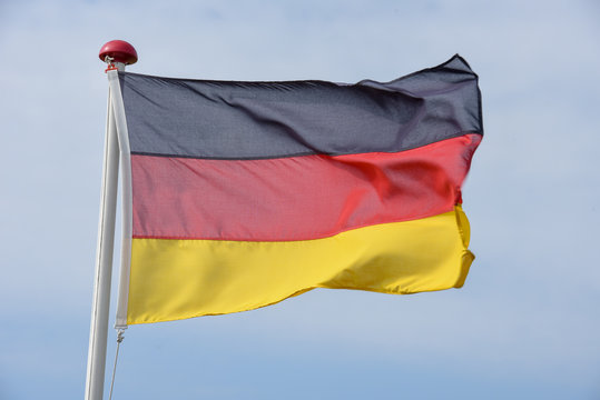German flag waving on the wind against blue sky