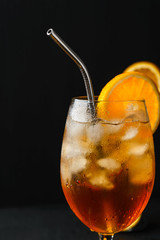Alcoholic cocktail Aperol Spritz in a wine glass covered with water drops, slice of orange ,ice cubes and metal straw
