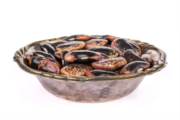 Lot of whole stained purple bean in metal bowl isolated on white background