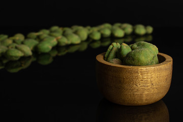 Lot of whole spicy green wasabi peanut large group is in the back and small group is in the front isolated on black glass