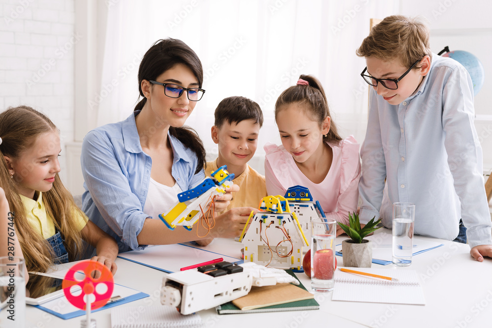 Aufkleber School children constructing robots with teacher in class