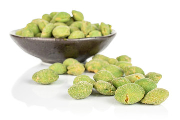 Lot of whole spicy green wasabi peanut small group is aside and the rest is in dark ceramic bowl isolated on white background