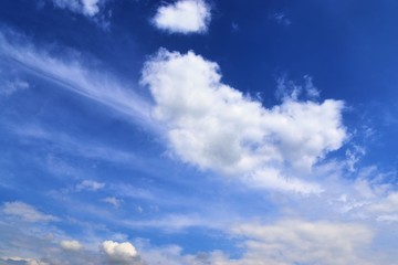 Dramatic and fluffy white clouds on a deep blue summer sky 