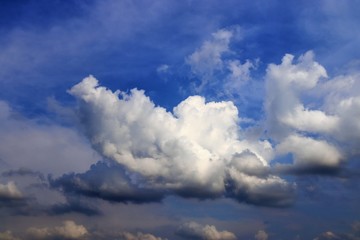 Dramatic and fluffy white clouds on a deep blue summer sky 
