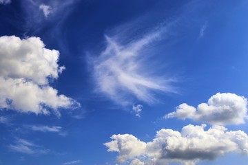 Dramatic and fluffy white clouds on a deep blue summer sky 