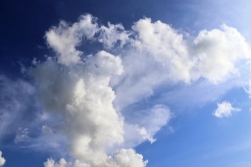 Dramatic and fluffy white clouds on a deep blue summer sky 