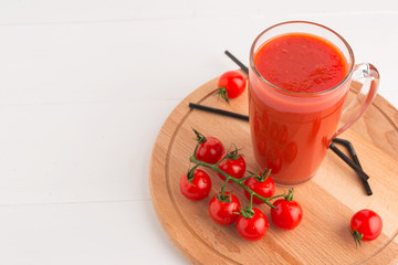 Fresh Tomato juice in a Cup on a wooden tray with cherry tomatoes