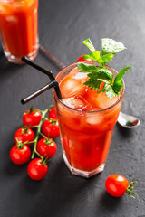 Bloody Mary alcoholic cocktail, celery branch and cherry tomatoes on dark background