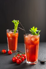 Bloody Mary alcoholic cocktail, celery branch and cherry tomatoes on dark background