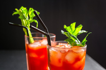 Bloody Mary alcoholic cocktail, celery branch and cherry tomatoes on dark background