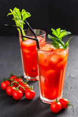 Bloody Mary alcoholic cocktail, celery branch and cherry tomatoes on dark background