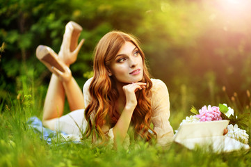 Beautiful young woman lying on green meadow