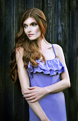 Fototapeta premium Beautiful young woman posing near the wooden wall