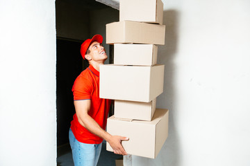 Funny nervous man is carrying his stuff in boxes to the recently bought flat. He is holding cardboard boxes and one is falling down, isolated on yellow background
