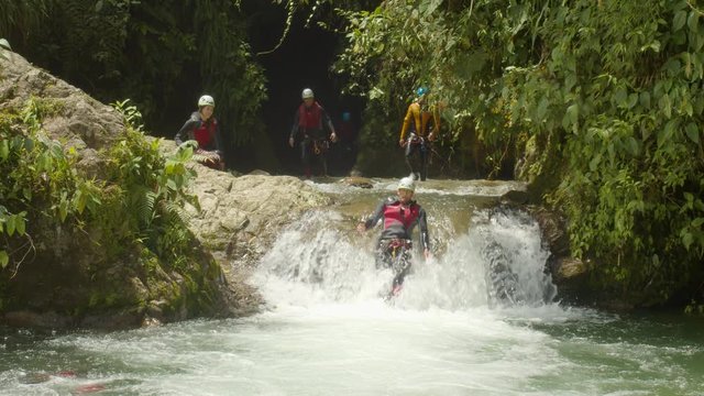 Adult Tourist Man Doing Canyoning Throwing Himself Into A Crystal Clear Waterfall In Ecuador