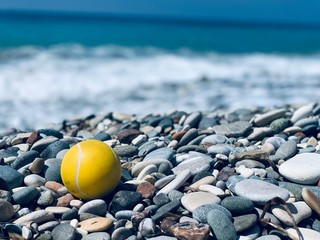 yellow tennis ball on the stones on the beach