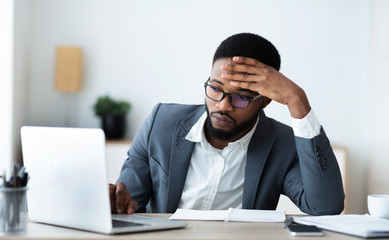 Thoughtful employee using laptop working on new project