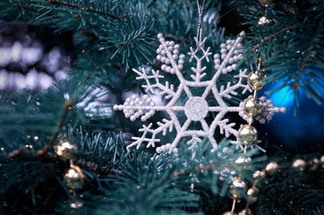 Obraz na płótnie Canvas close-up of a Christmas tree with rose gold and turquoise decorations (balls, snowflakes, bows, beads) on a blurry background with snow. Christmas and New Year holidays background