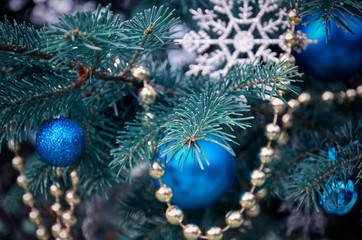 close-up of a Christmas tree with rose gold and turquoise decorations (balls, snowflakes, bows, beads) on a blurry background with snow. Christmas and New Year holidays background