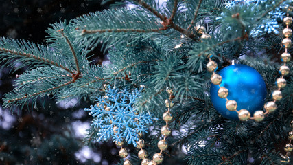 Obraz na płótnie Canvas close-up of a Christmas tree with rose gold and turquoise decorations (balls, snowflakes, bows, beads) on a blurry background with snow. Christmas and New Year holidays background