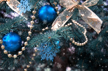 close-up of a Christmas tree with rose gold and turquoise decorations (balls, snowflakes, bows, beads) on a blurry background with snow. Christmas and New Year holidays background