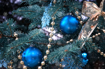 close-up of a Christmas tree with rose gold and turquoise decorations (balls, snowflakes, bows, beads) on a blurry background with snow. Christmas and New Year holidays background