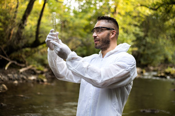 Scientist in protective suits takeing water samples from the river,stock photo