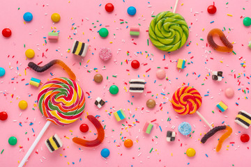 flat lay of candies festive background with assortment of colourful caramel with jelly and sprinkles over pink