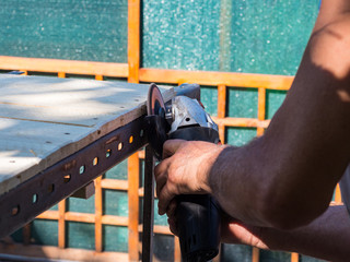 Man working with angle grinder and flap disc as a Sander on wooden shelf