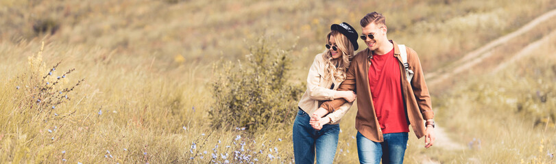 panoramic shot of attractive woman and handsome man smiling and holding hands