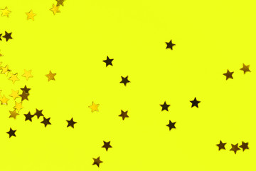 Golden decorative stars on yellow background. Holiday and festive concept