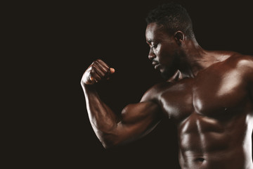 Handsome black bodybuilder demonstrating his arm strength