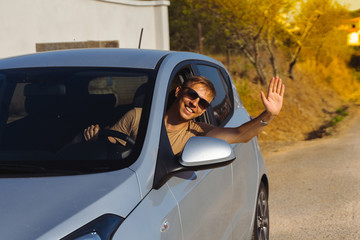 happy man saluting hand out of window car. traveler enjoying road trip. car on asphalt road in nature or the highway. travel by car concept.