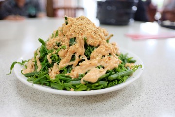 Boiled fern salad with a spicy sauce on top,dinning table background