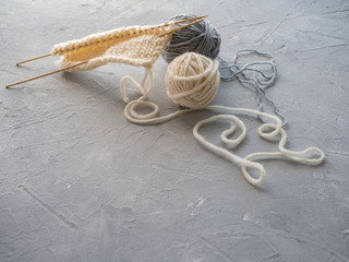 Two balls of wool and knitting a scarf with wooden spokes. The concept of needlework, handmade.