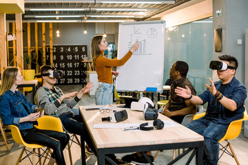 Friends group testing on vr glasses indoors. Virtual reality and wearable tech concept with young people having fun together with headset goggles. Young woman having speech