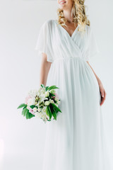 cropped view of bride in wedding dress holding bouquet isolated on white