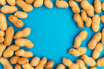 Inshell peanuts on a blue background, space for text