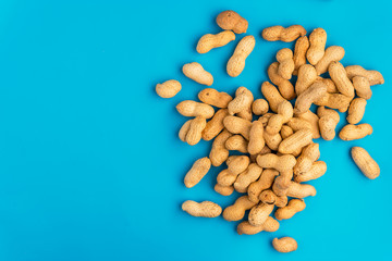 Fototapeta na wymiar Inshell peanuts on a blue background, space for text