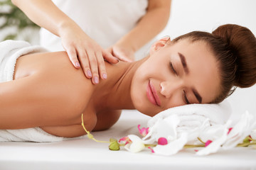 Fototapeta na wymiar Young woman enjoying back massage in spa salon