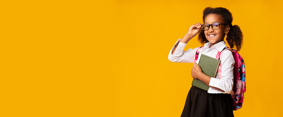 Black Schoolgirl Posing With Books Over Yellow Background