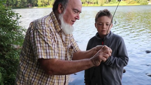 Adult showing child how to remove a fish hook. 