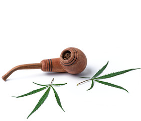 wooden smoking pipe and green hemp leaves on a white background