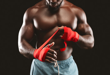 Professional black sportsman rolling boxing wraps over wrists
